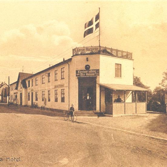 Sort-hvid foto: Tølløse Hotel med tagterrasse, flag - og reklame for Korsør Margarine. Set fra gaden.