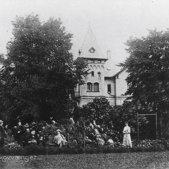 Sort-hvid postkort med hotellets tårn og gæster i haven foran.