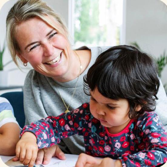 Kvinde med barn ved bord.