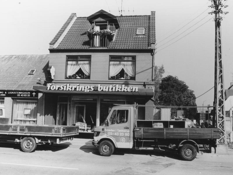 Sort-hvid foto: Forsikringsbutikken på Labæk 25. Foran facaden holder to lastvogne.