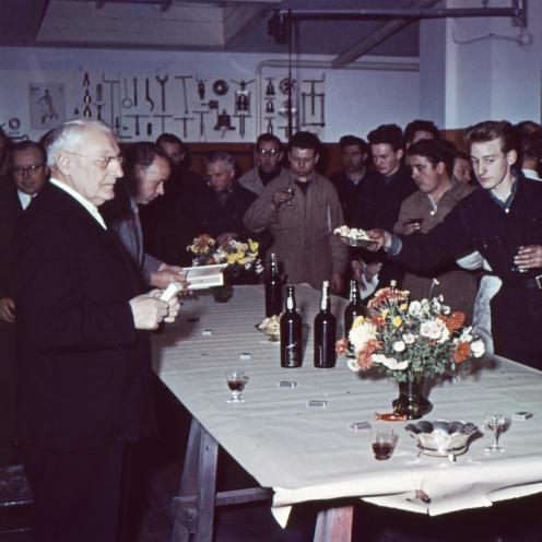 Farvefoto af stående gæster rundt om et bord til reception.