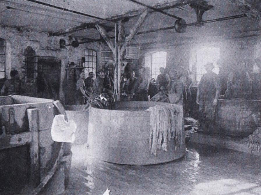 Sort-hvid foto: En gruppe arbejdere samlet om et stort kar.