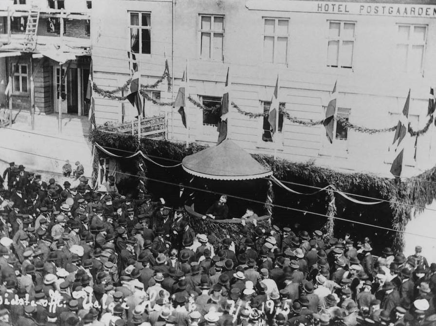 Sort-hvid foto af en menneskemængde, der ser mod en overdækket talerstol.