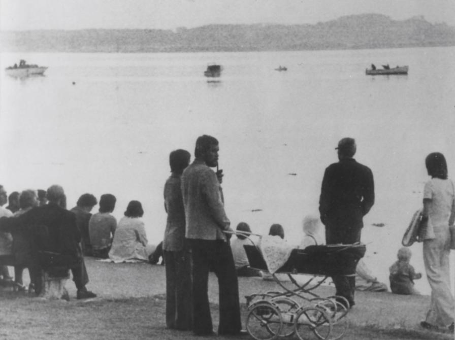 Sort-hvid foto af folk ved stranden, som ser ud over fjorden.