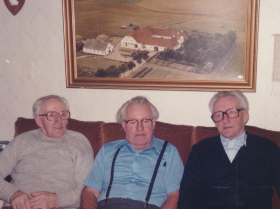 Farvefoto af tre ældre mænd siddende i sofa.