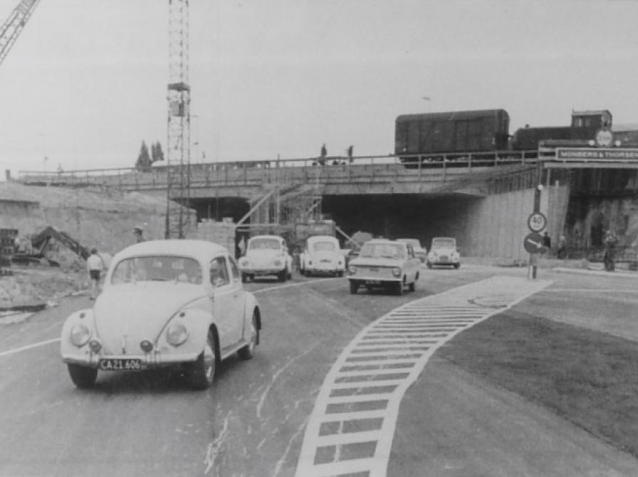 Sort-hvid foto af biler, der kører gennem en tunnel med kran og andet byggeri udenom.
