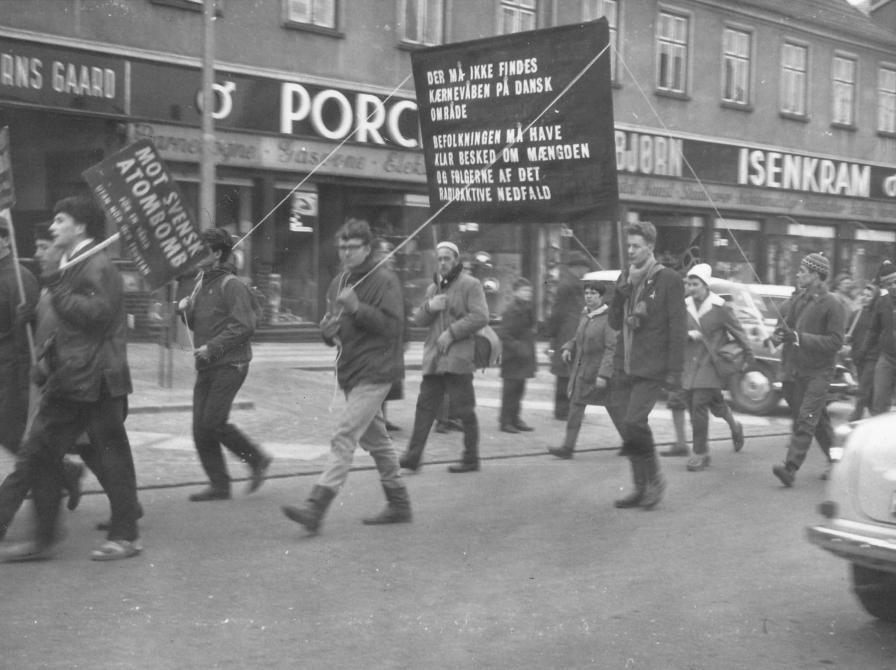 Sort-hvid foto af en gruppe mennesker med skilte, der går i flok ned ad Ahlgade.